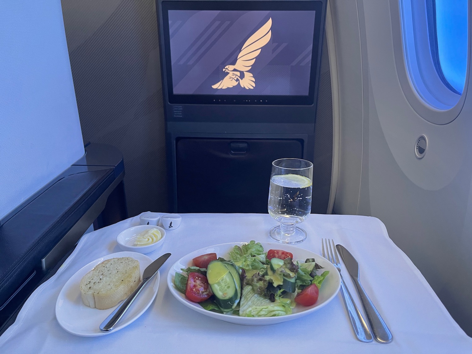 a plate of salad and a glass of water on a table with a television