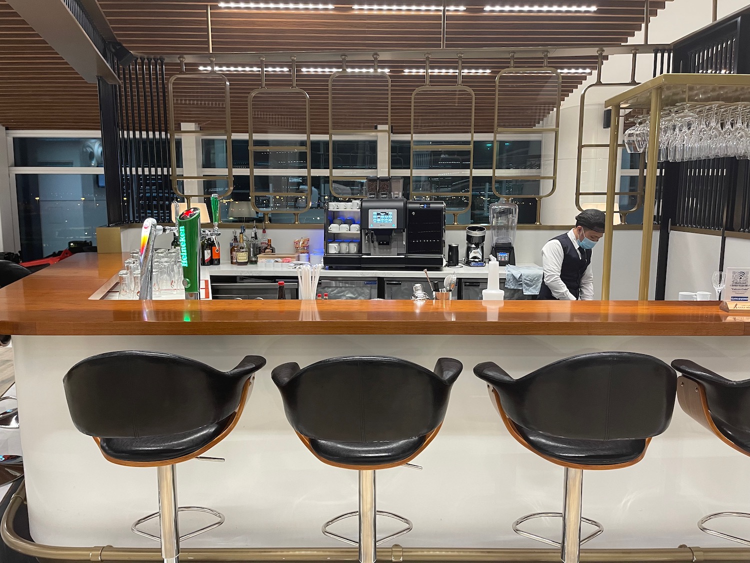 a bar with chairs and a person behind it