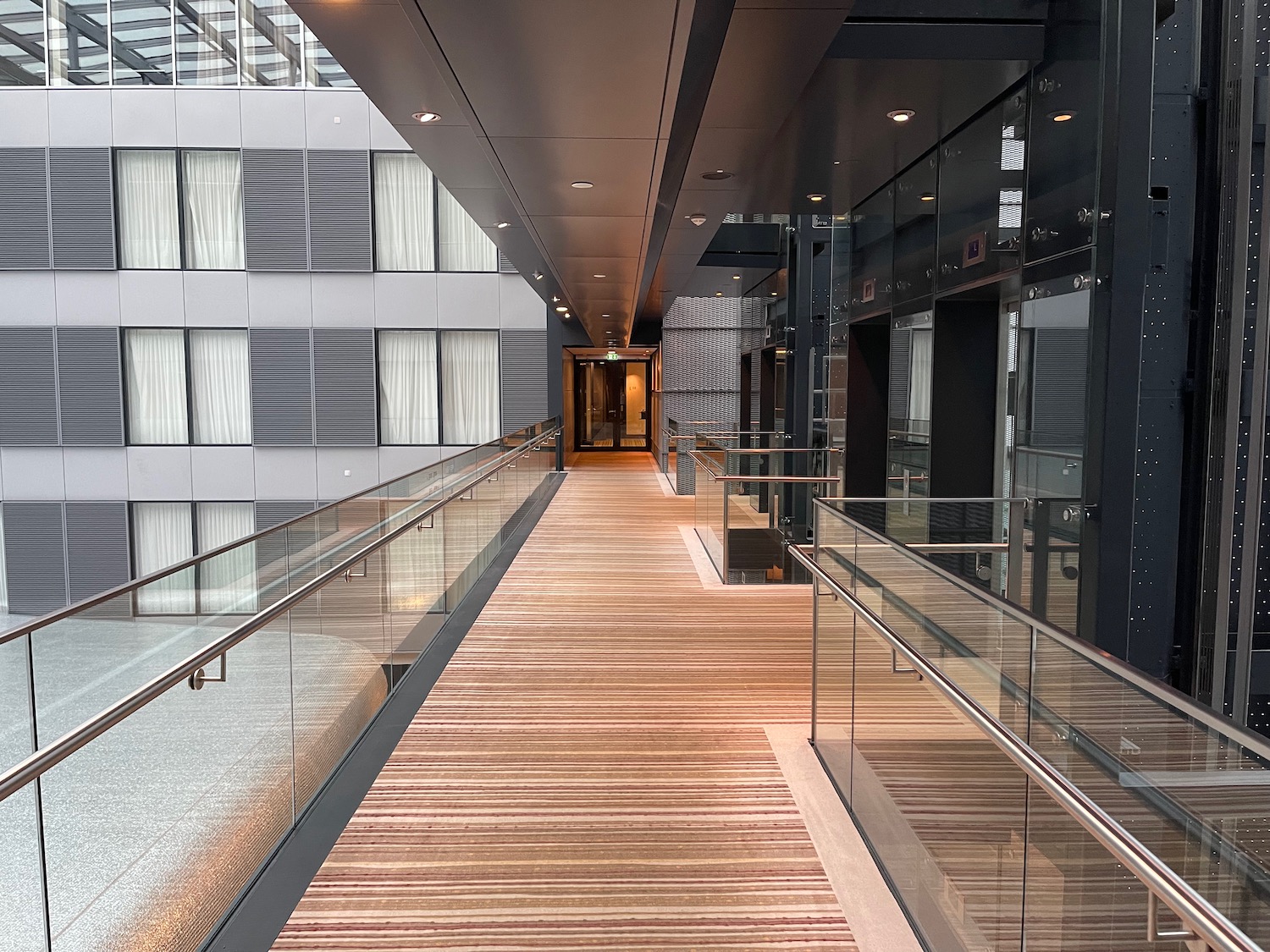 a walkway with glass railings and a wood floor