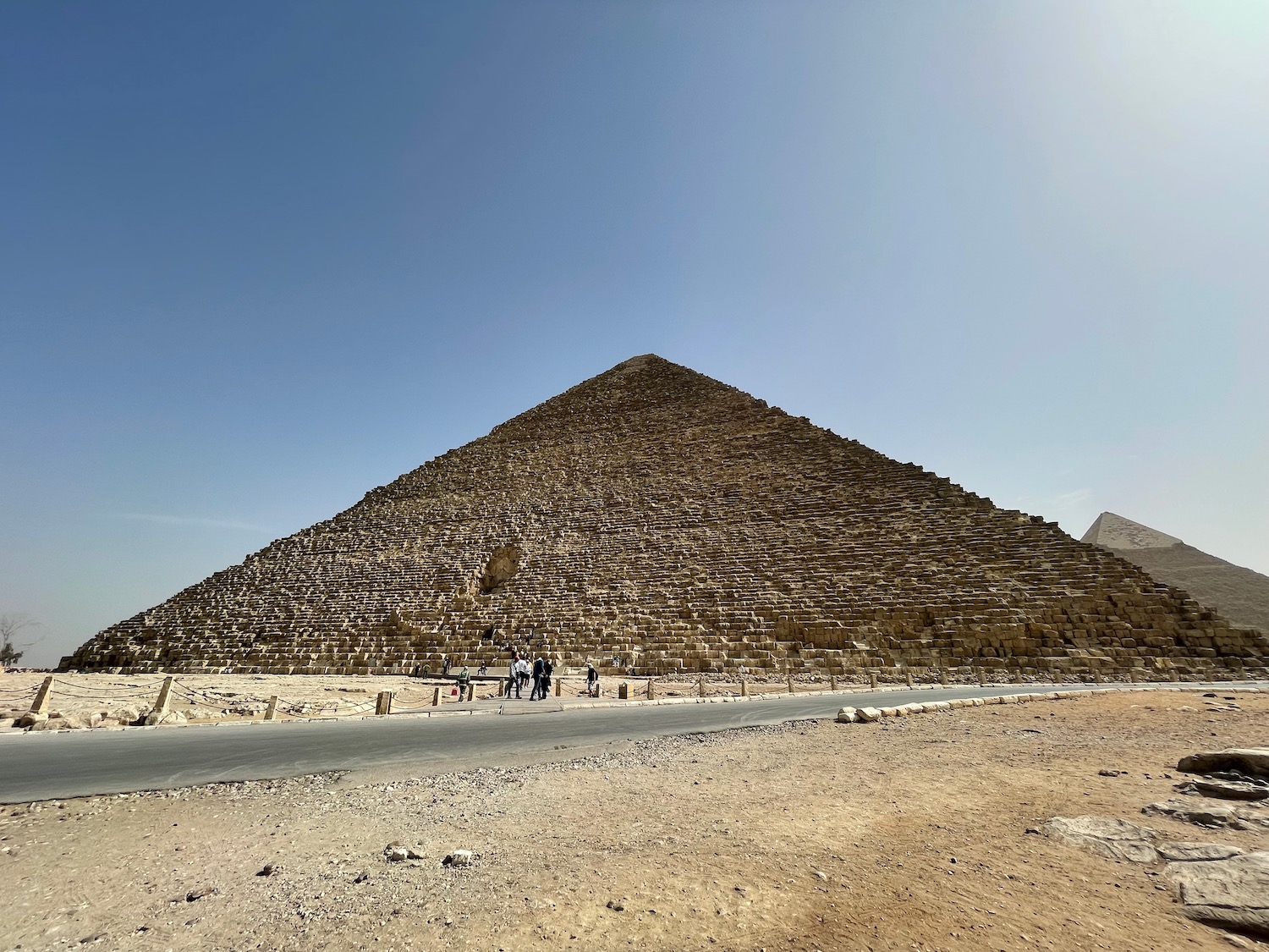 a pyramid with people walking on the side with Pyramid of Menkaure in the background