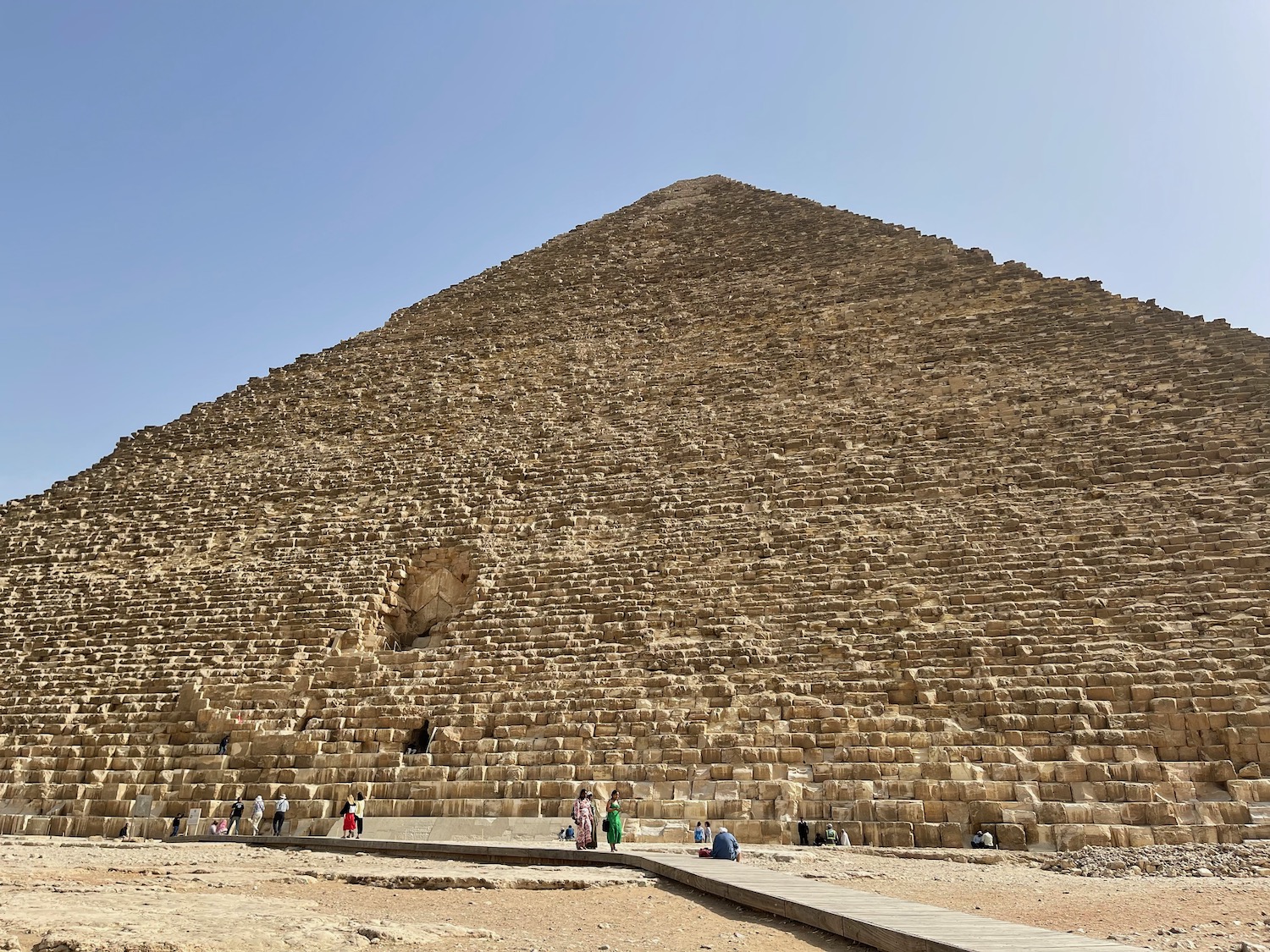 a pyramid with people walking around with Great Pyramid of Giza in the background