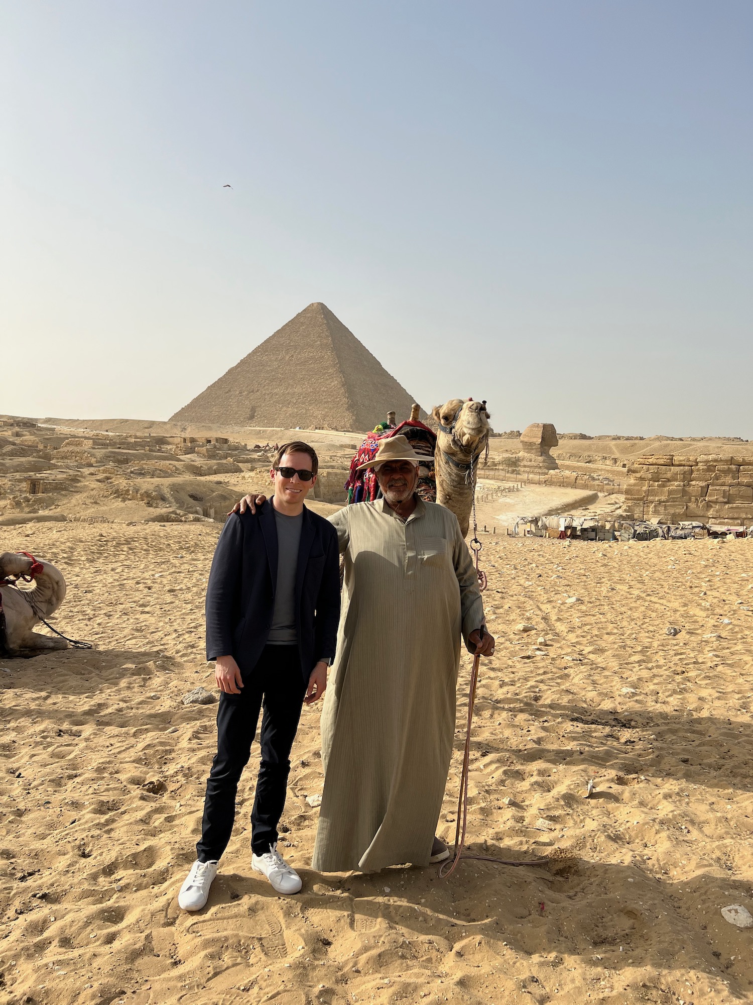 a man and a camel posing in front of a pyramid