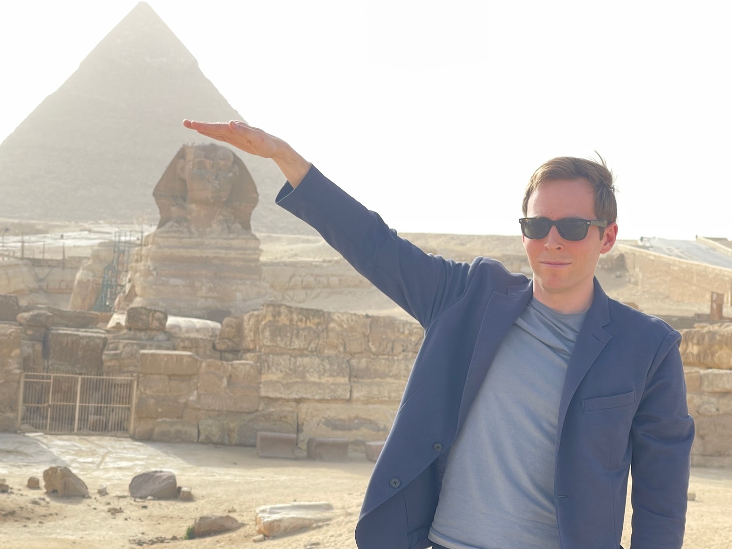 a man in sunglasses holding his hand up in front of a pyramid