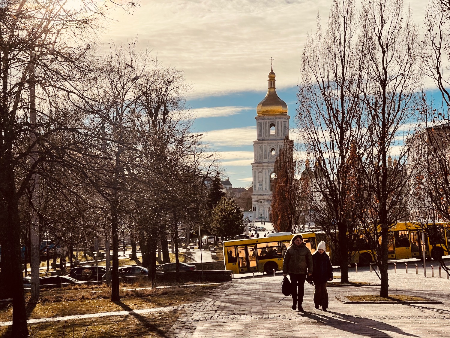 people walking on a brick path with trees and a building in the background