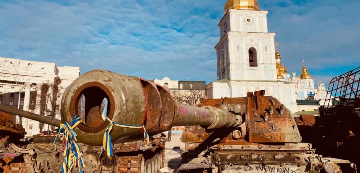 a tank with a large barrel in front of a building