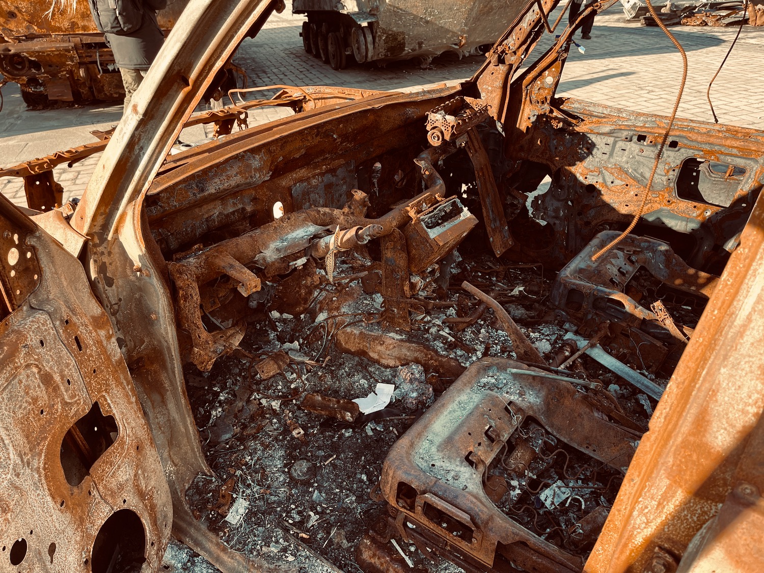 a burned out car with a person standing next to it