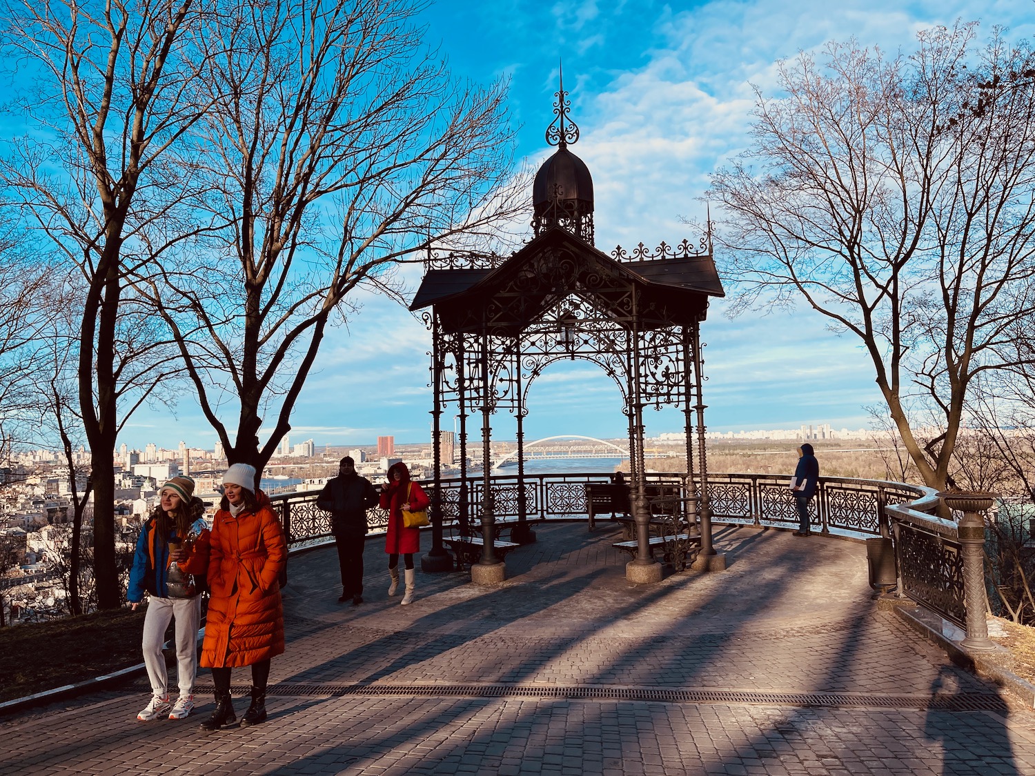 people standing on a walkway with a gazebo and people walking around