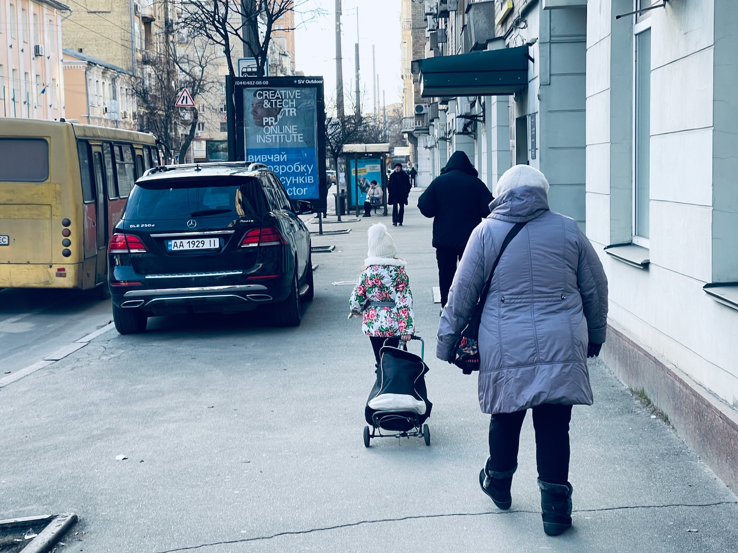 people walking down a sidewalk with a child pushing a stroller