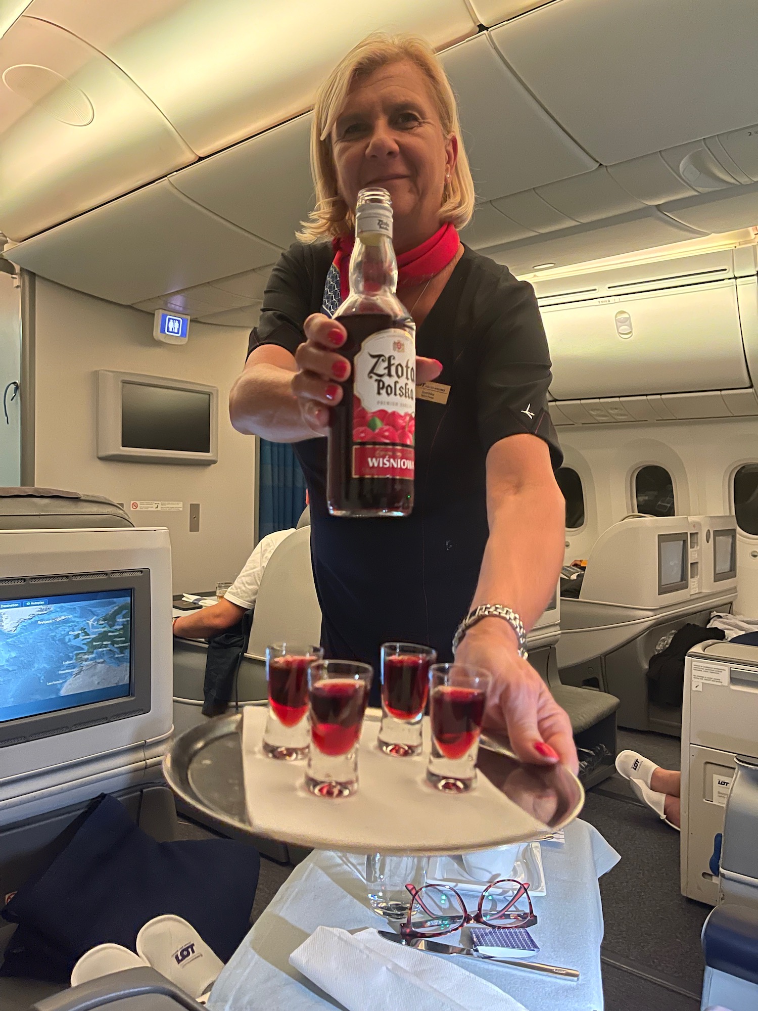 a woman holding a tray of shots and a bottle of liquor