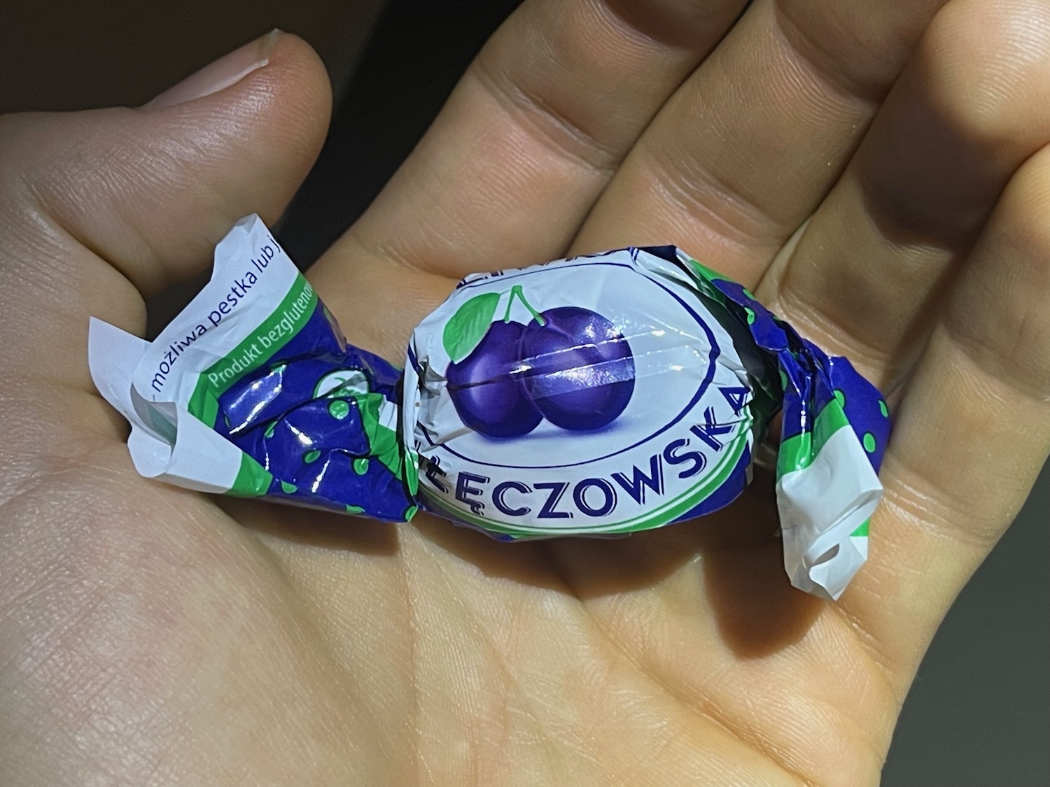 a hand holding a wrapped candy