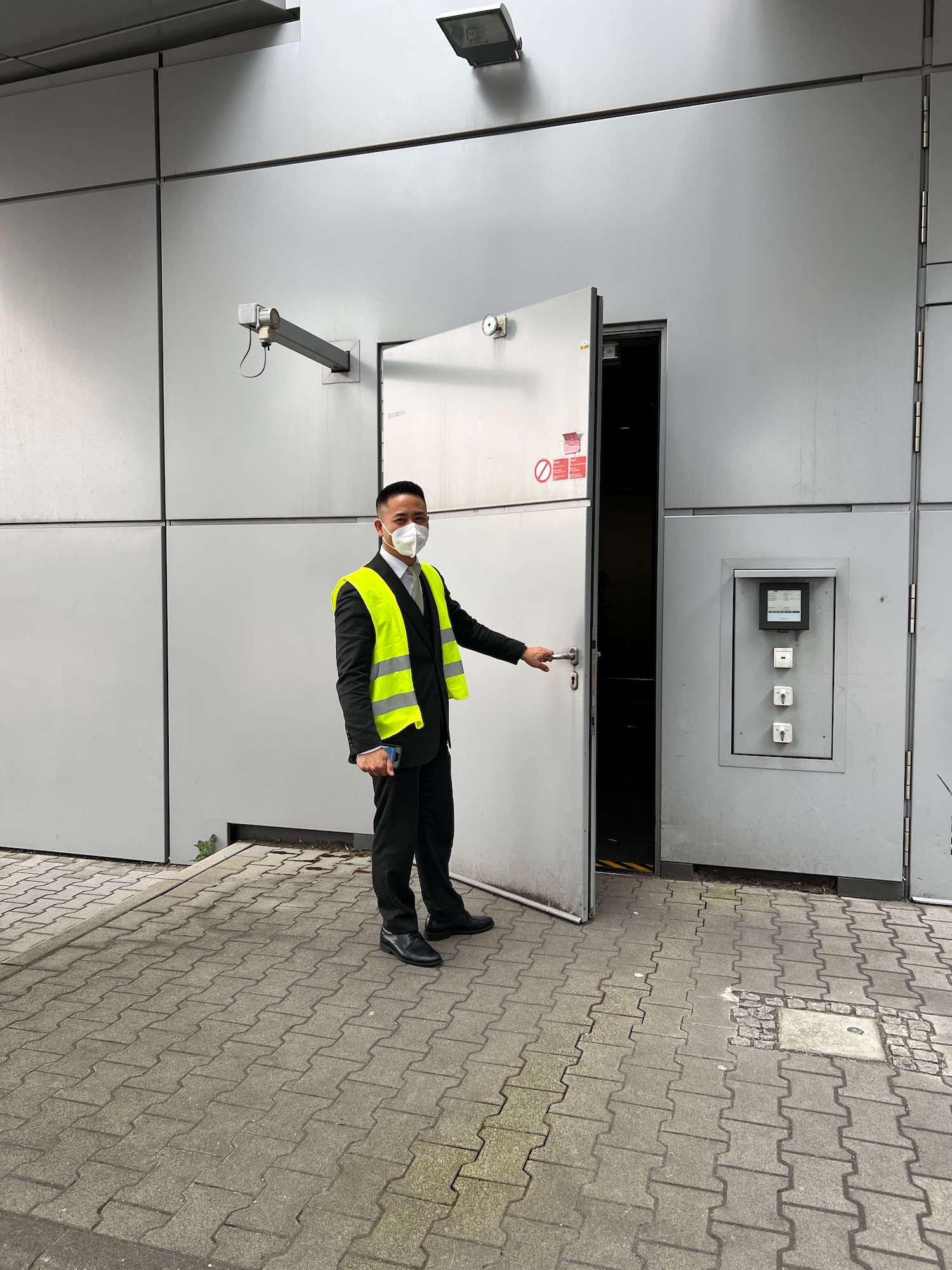 a man wearing a face mask and a yellow vest and a mask standing in front of a door