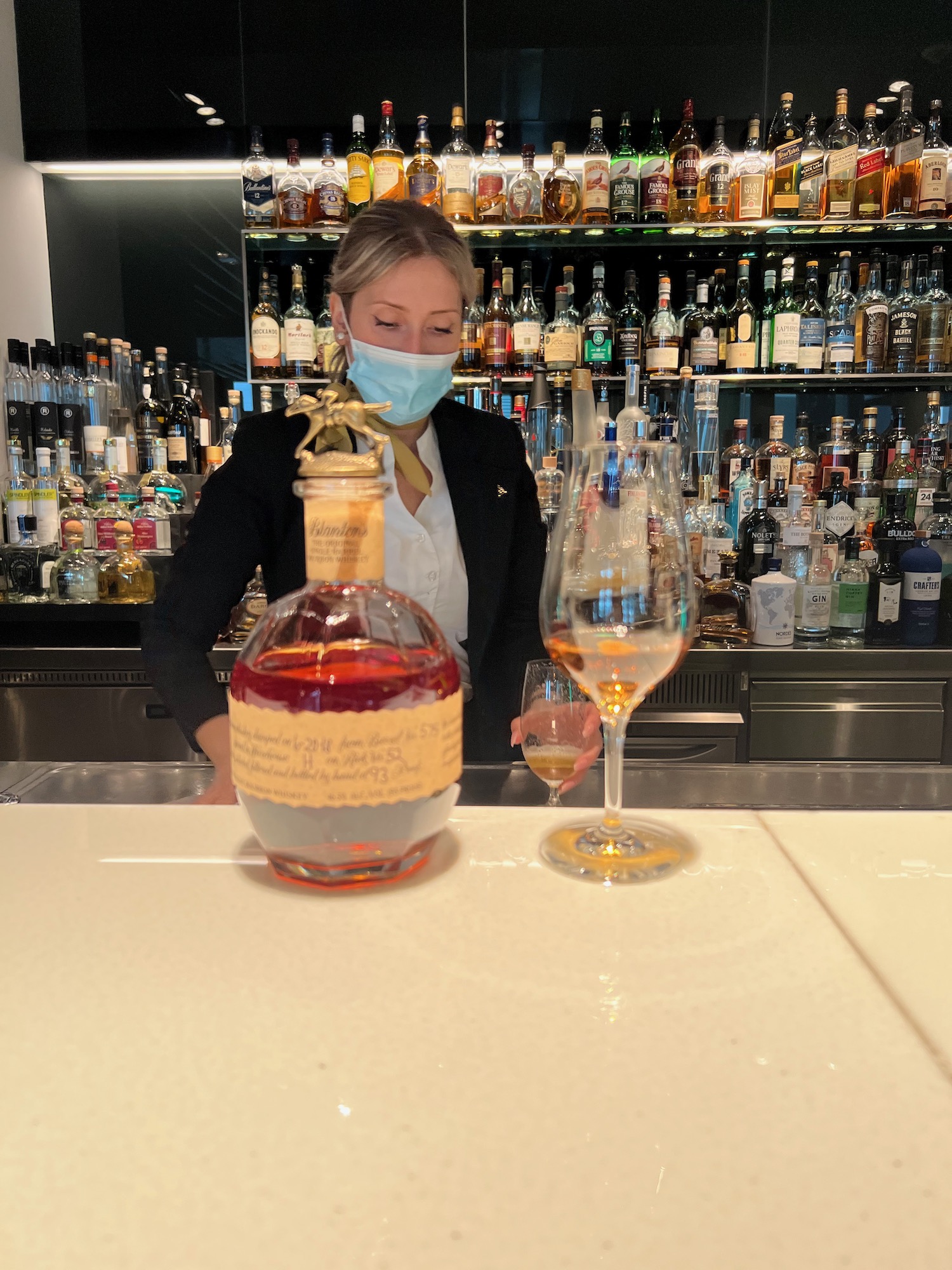 a woman wearing a face mask standing at a bar