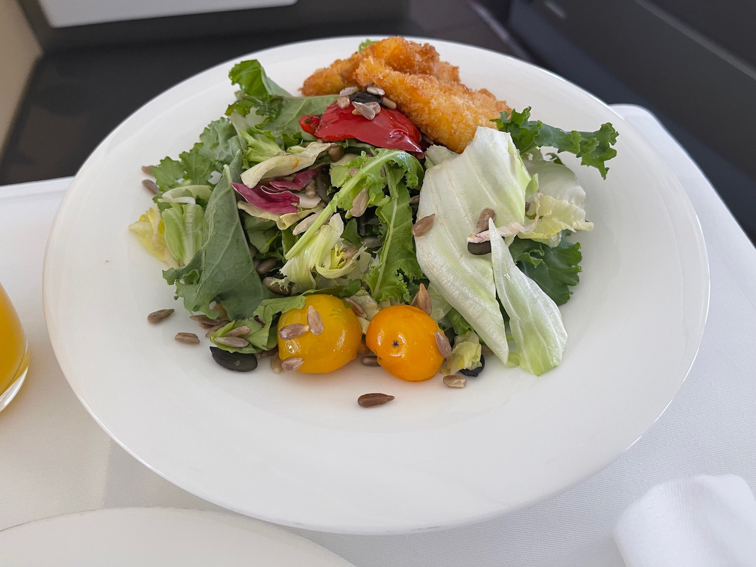 a plate of salad with chicken nuggets and tomatoes