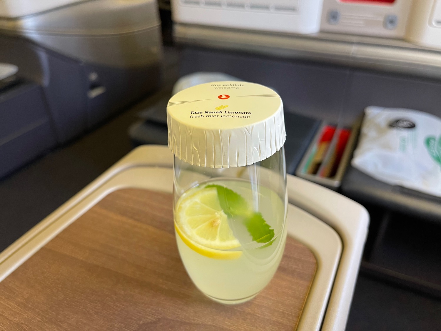 a glass of water with a lemon and mint leaf on a tray