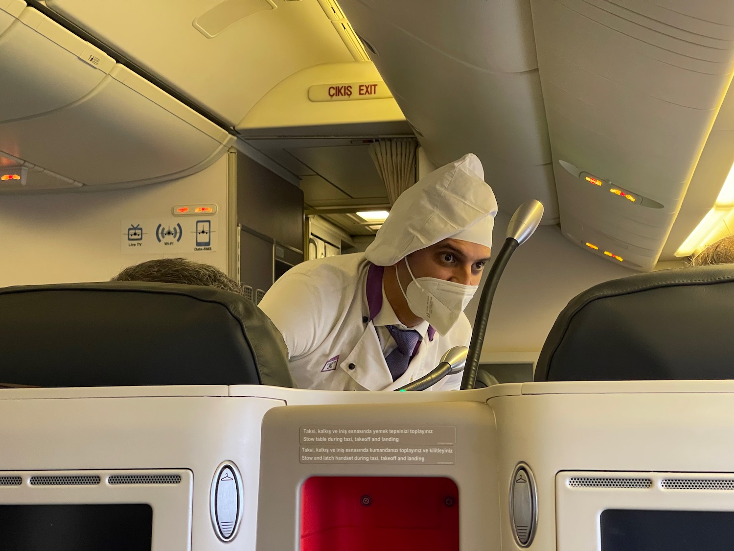 a man in a white coat and mask on an airplane