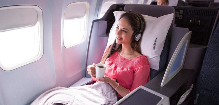 a woman sitting in a chair with headphones holding a cup of coffee