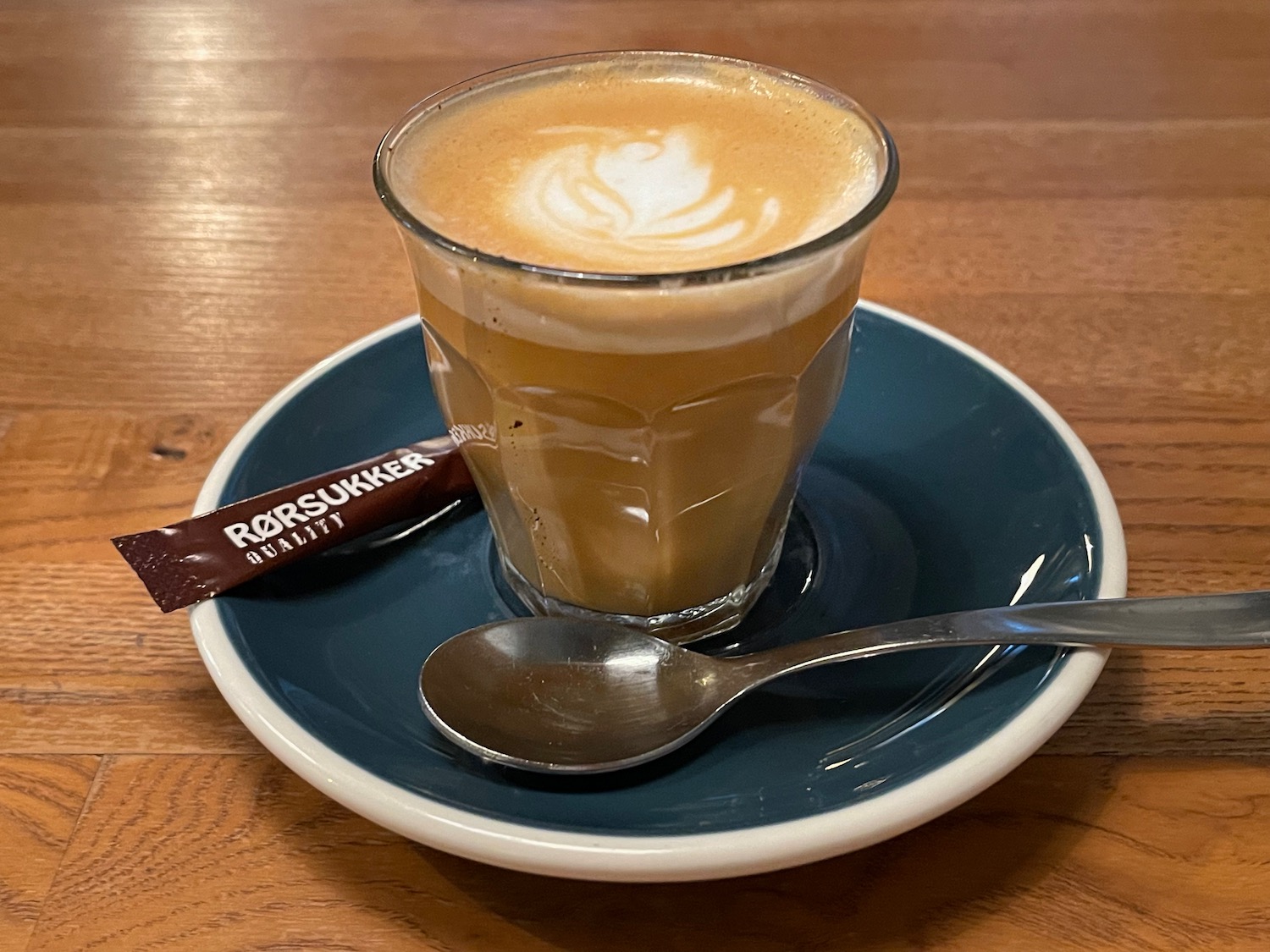 a cup of coffee on a plate with a spoon