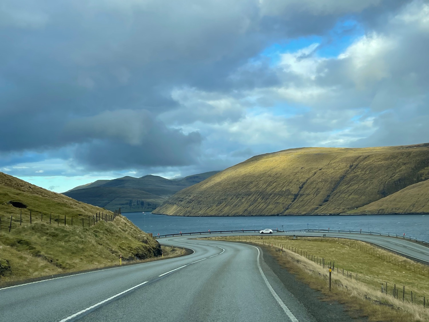 a road with a body of water and hills