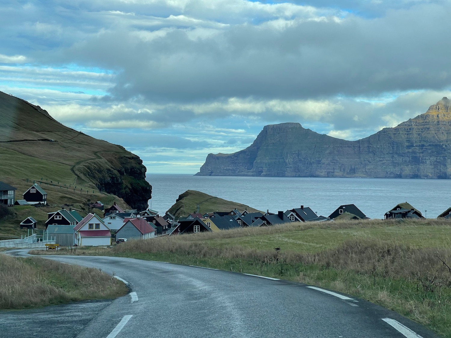 a road leading to a town with houses and a body of water