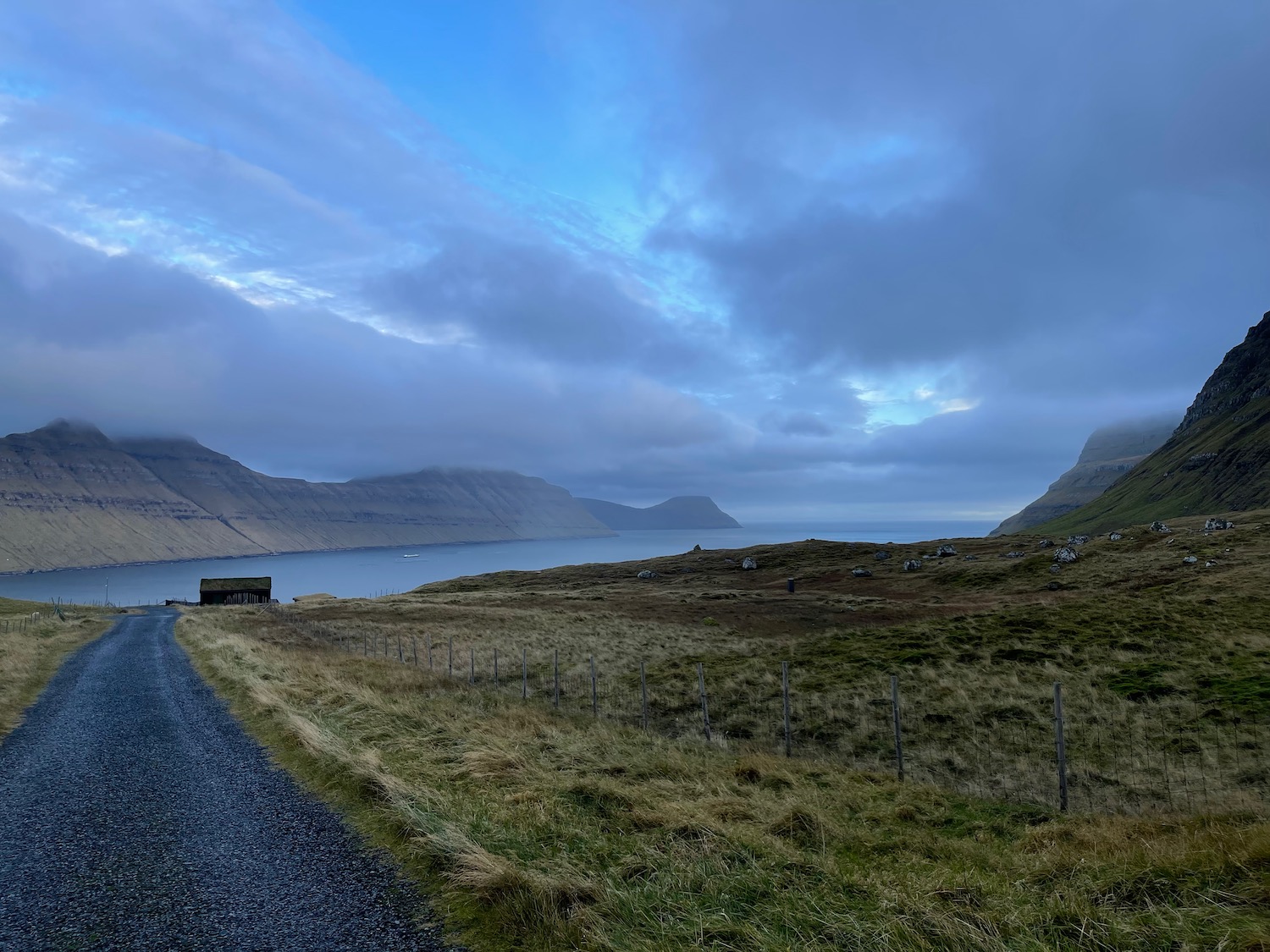 a gravel road next to a body of water