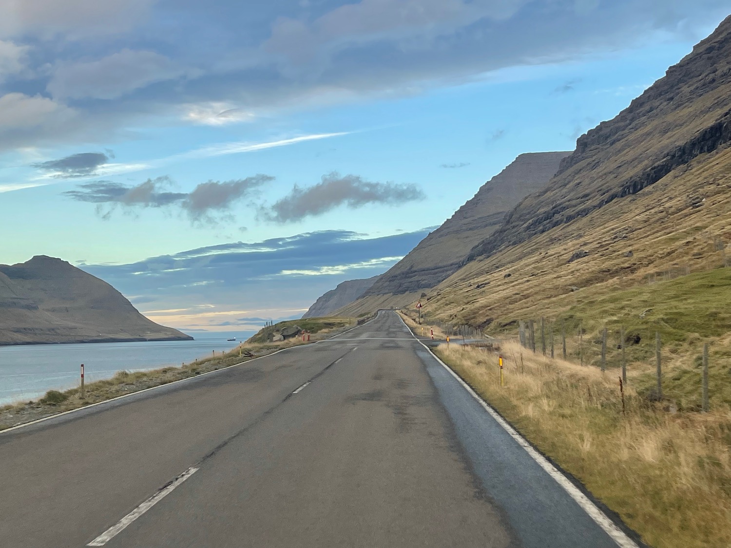 a road with grass and mountains in the background