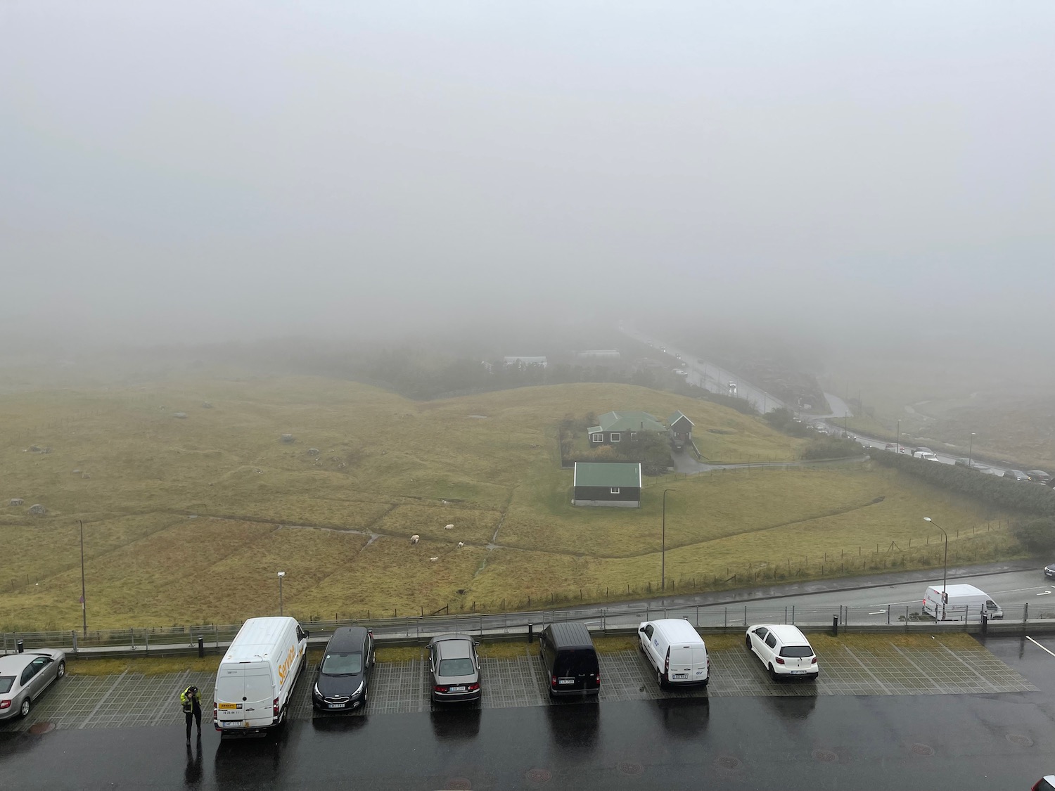 a parking lot with cars and a foggy landscape