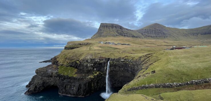 a waterfall on a cliff above water