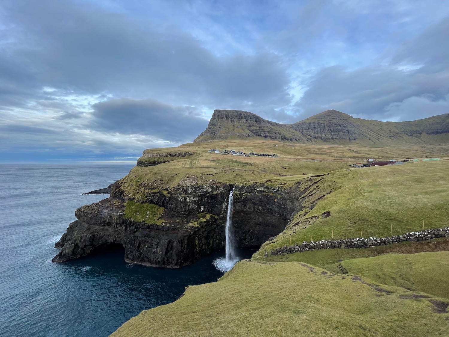 a waterfall on a cliff above water