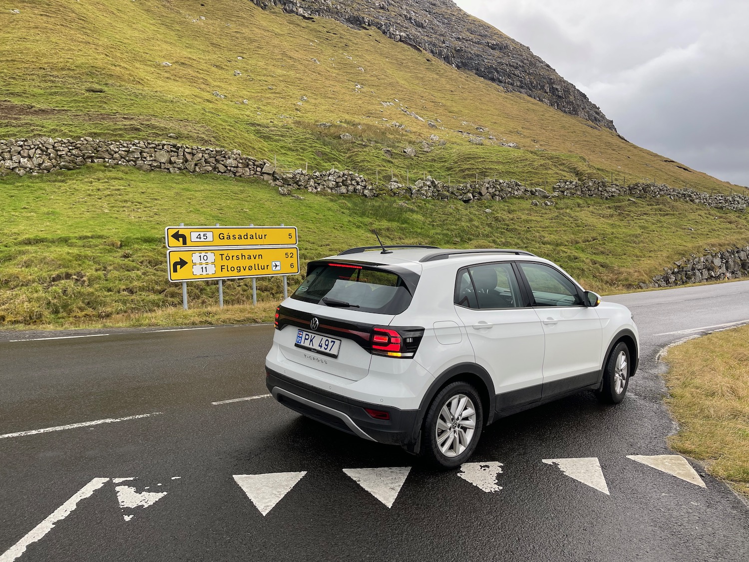 a white car on a road with a hill in the background