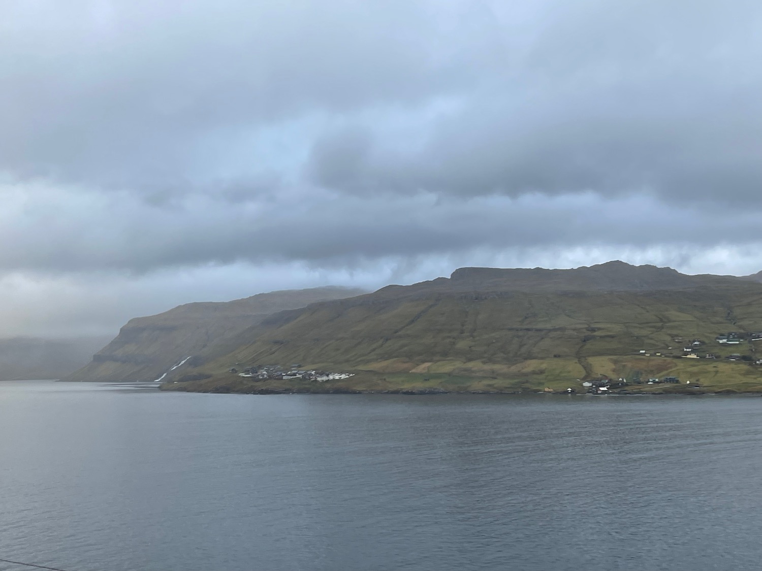 a body of water with a hill and a city on the side