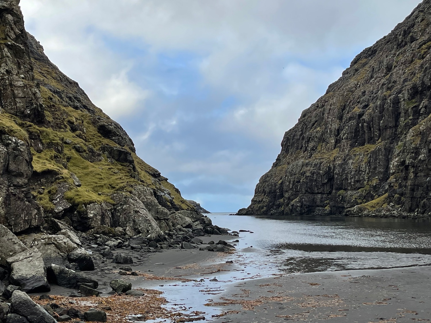 a rocky shore with a body of water and a rocky cliff with Hells Canyon in the background