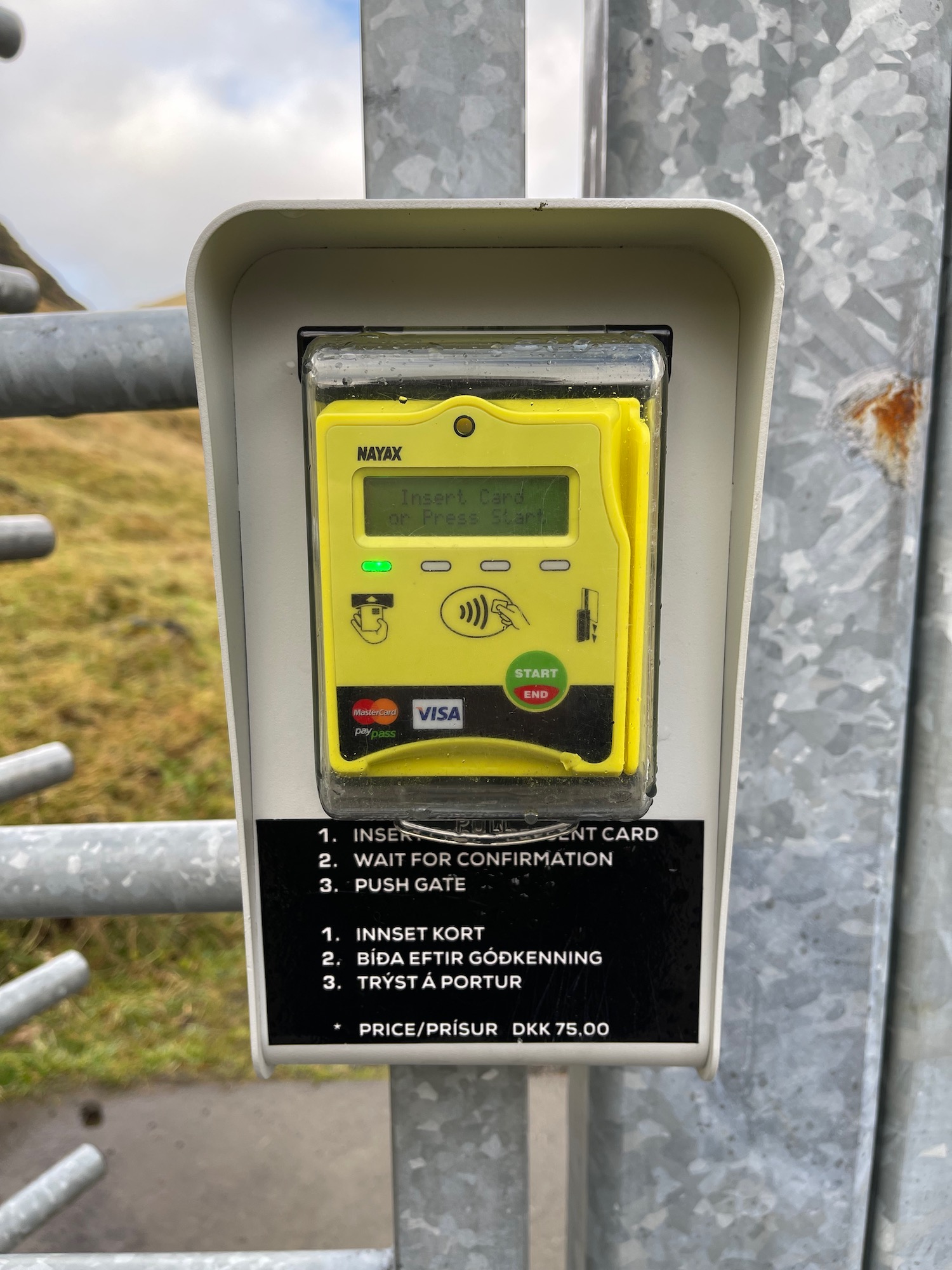 a yellow card reader on a metal fence