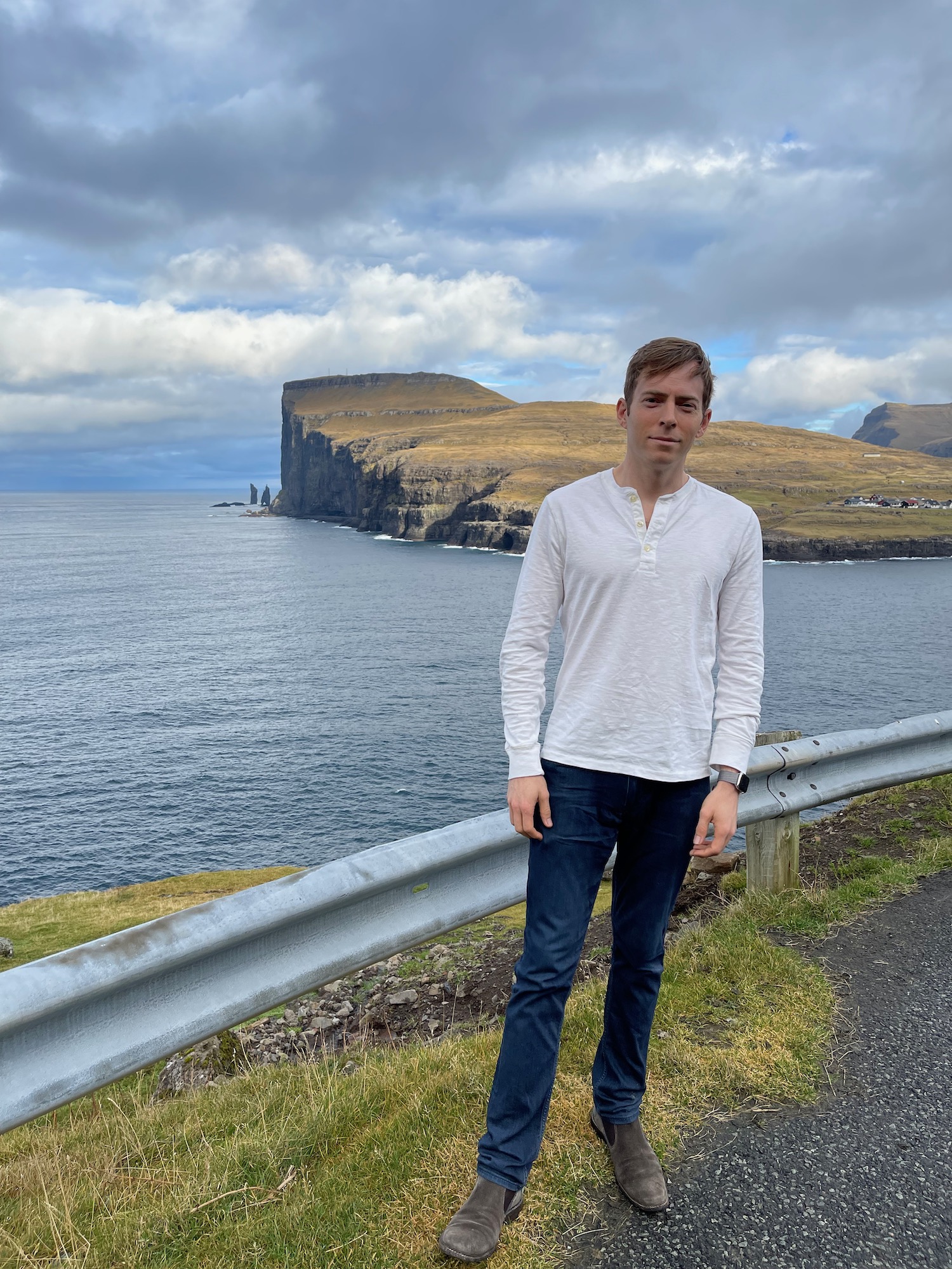 a man standing on a road next to a body of water