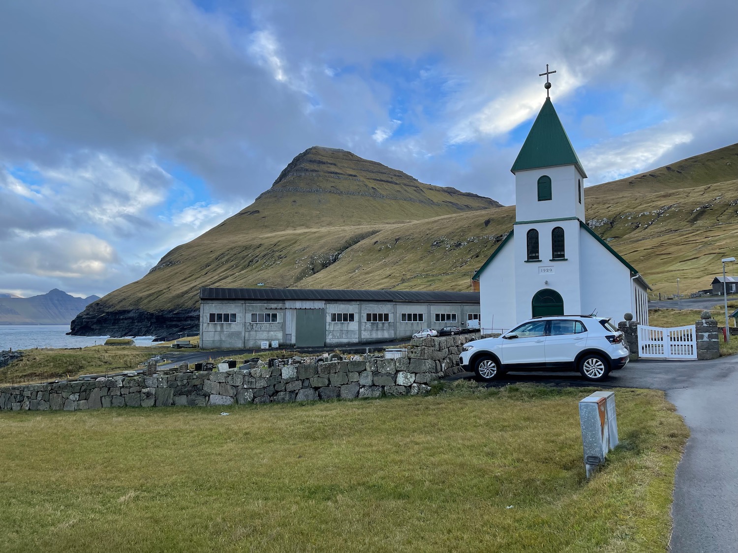 a white church with a car parked in front of a building