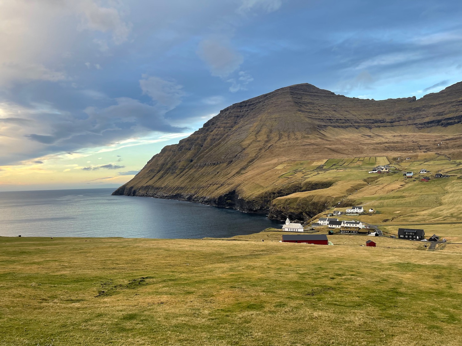 a landscape with a body of water and a hill and houses