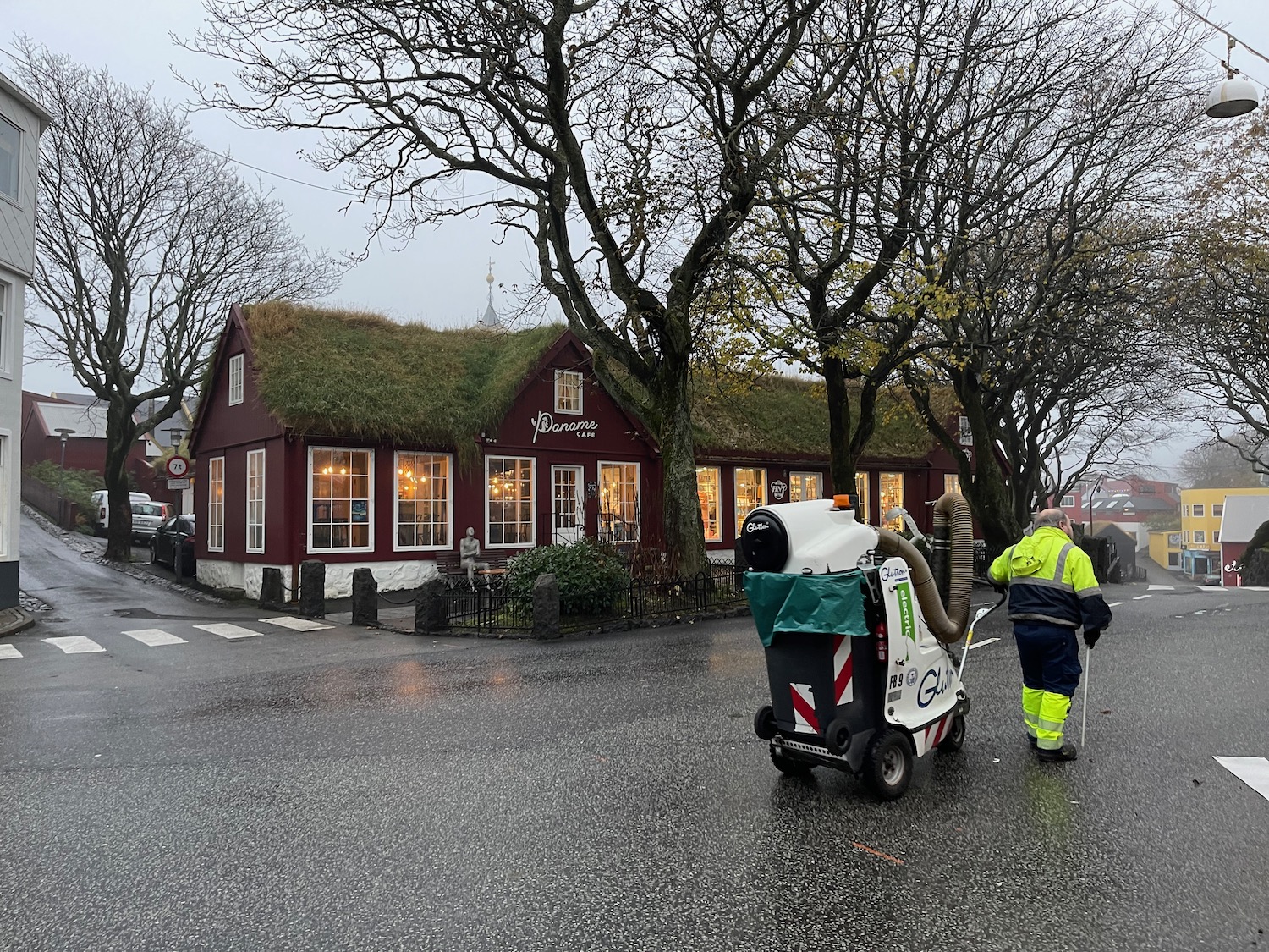 a man in a yellow vest pushing a machine on a street