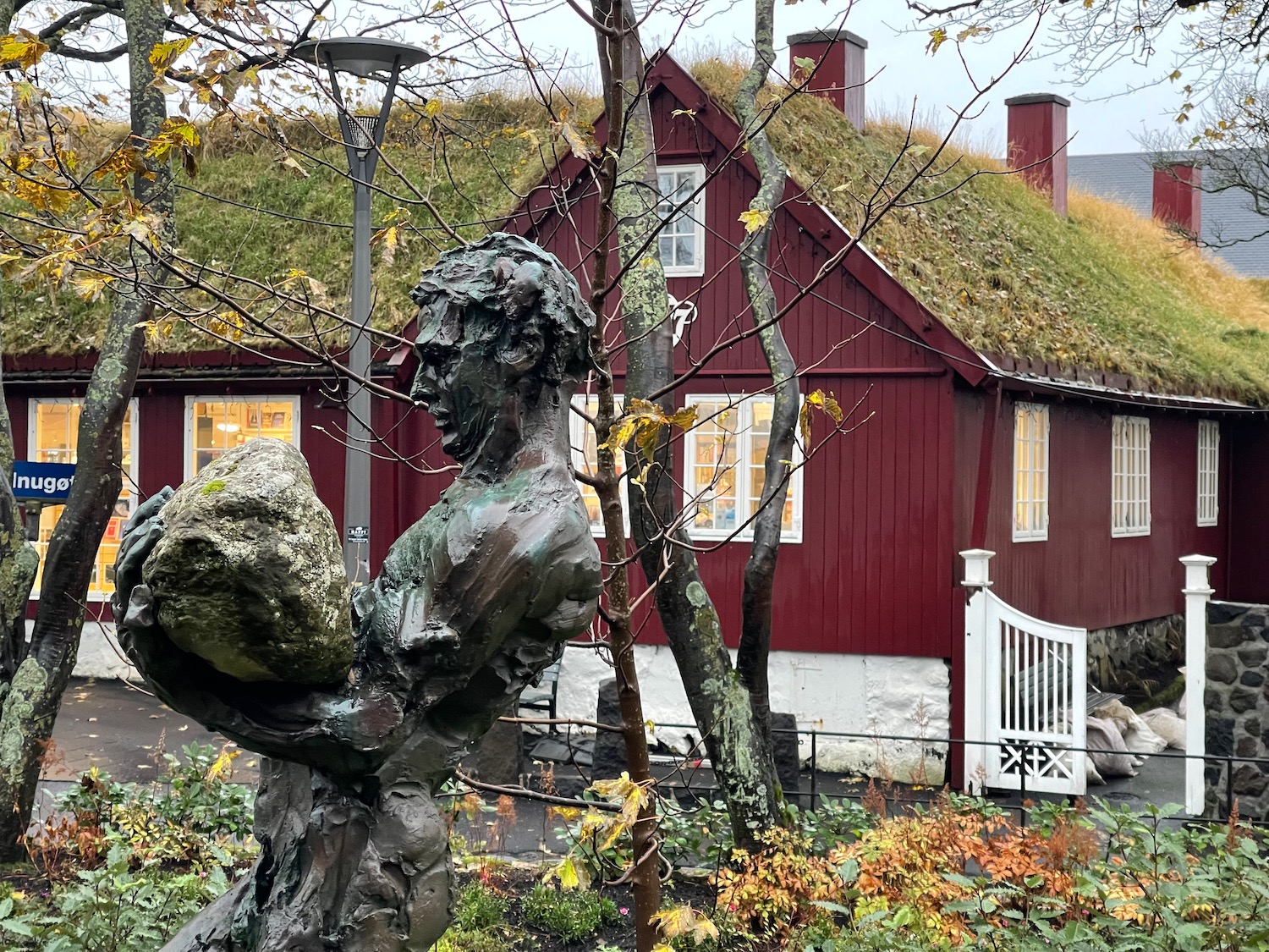 a statue of a man holding a rock in front of a red house