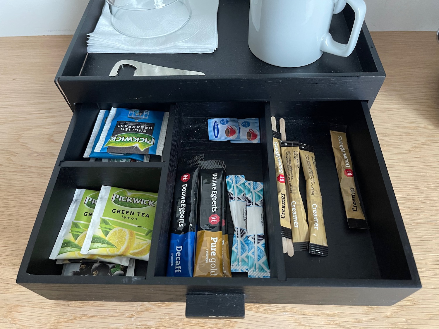 a black tray with a drawer full of tea packets and a mug