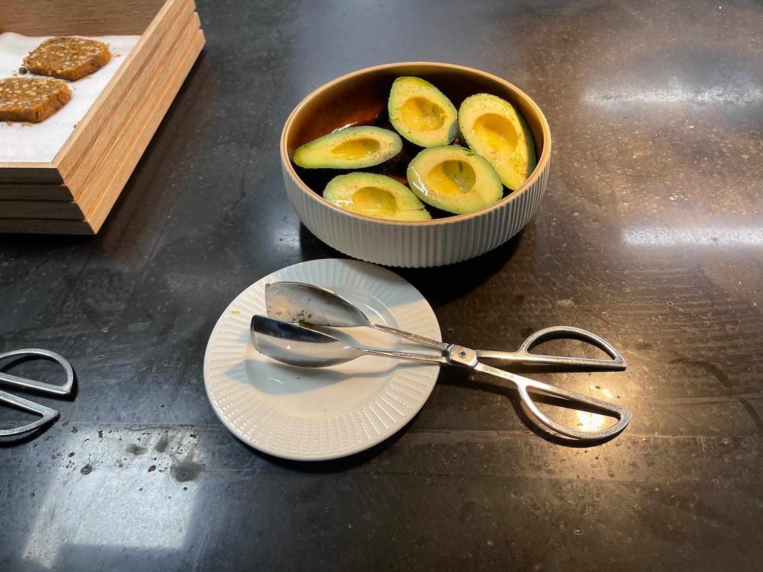 a bowl of avocado with a pair of tongs on a plate