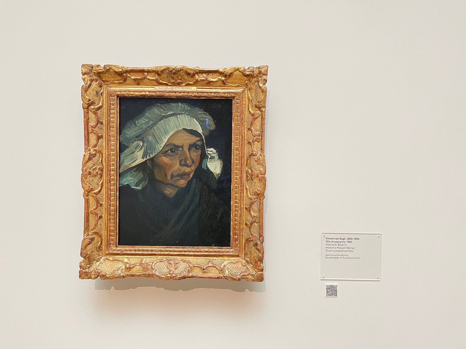a painting of a woman in a gold frame on a white wall