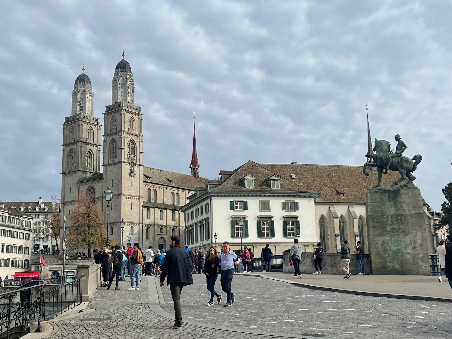 a group of people walking on a stone path with a stone building and towers