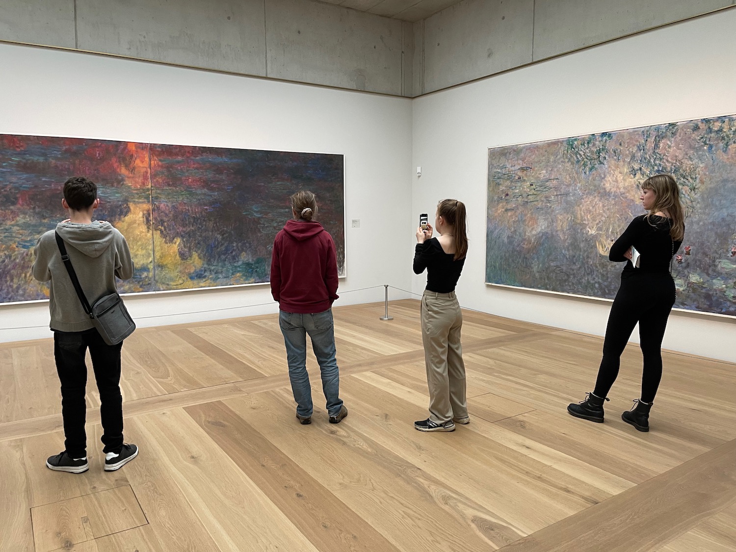 a group of people standing in a room with art on the wall