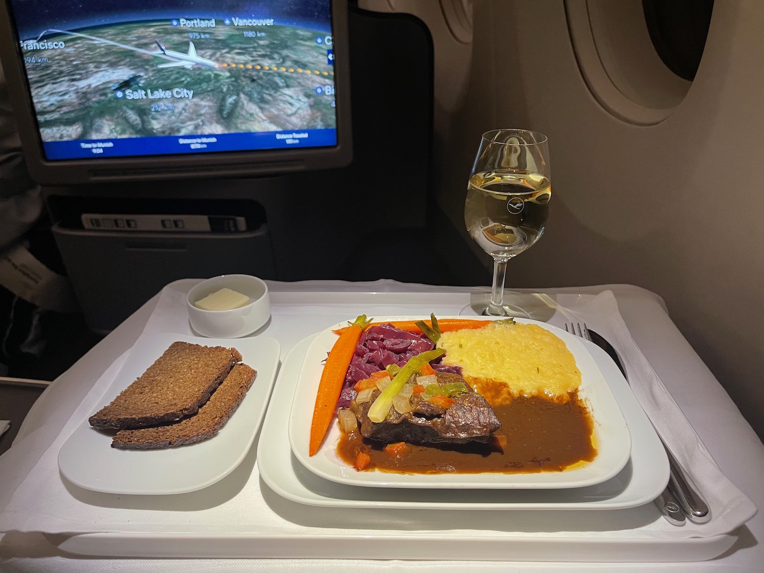 a plate of food and a glass of wine on a tray