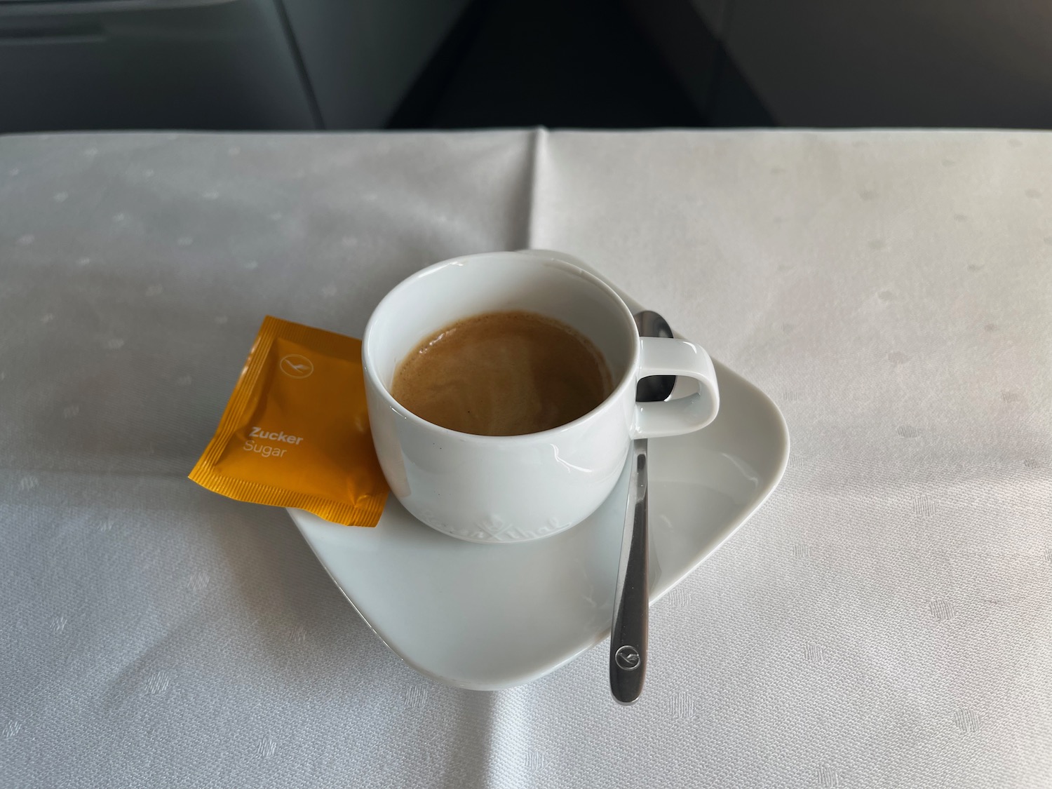 a cup of coffee on a saucer with a spoon and sugar packet