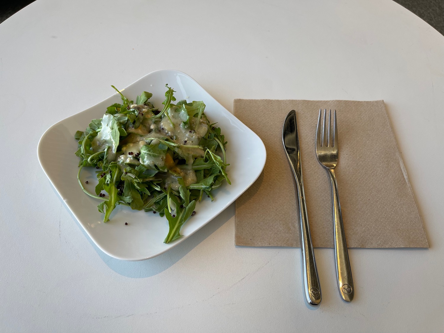 a plate of salad and fork on a napkin