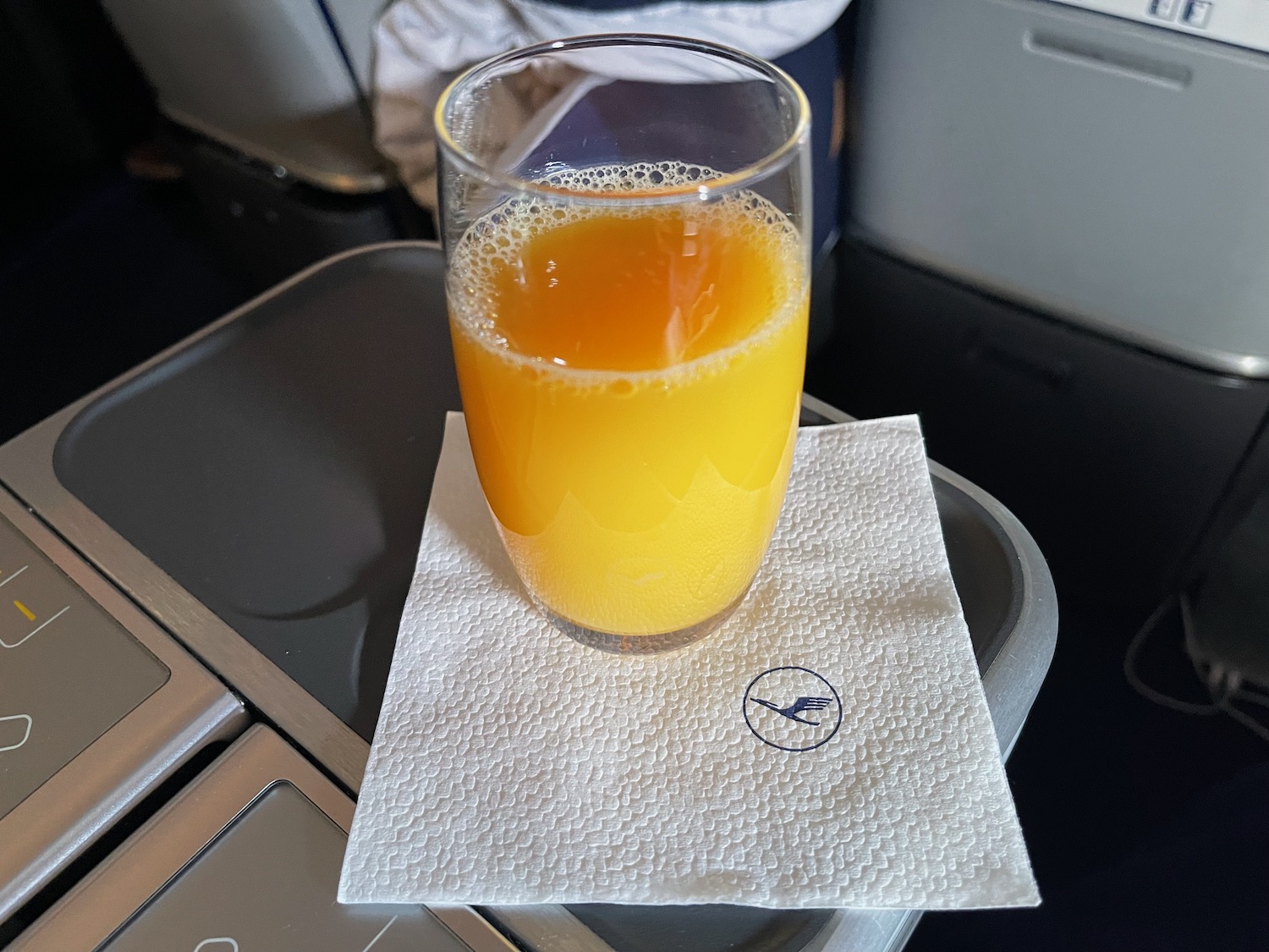 a glass of orange juice on a napkin on a tray