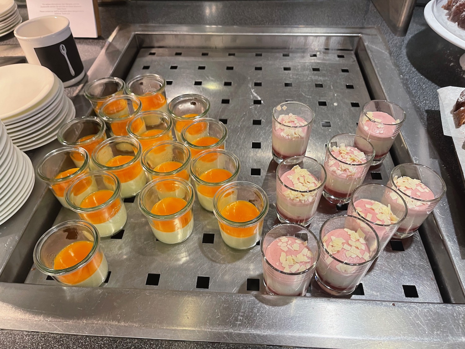 a group of small glasses of desserts on a metal tray