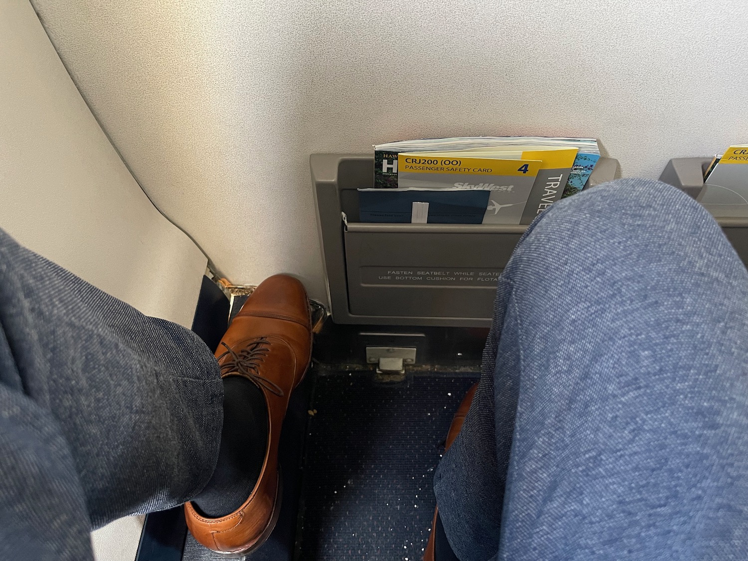 a person's feet in a seat with a magazine holder