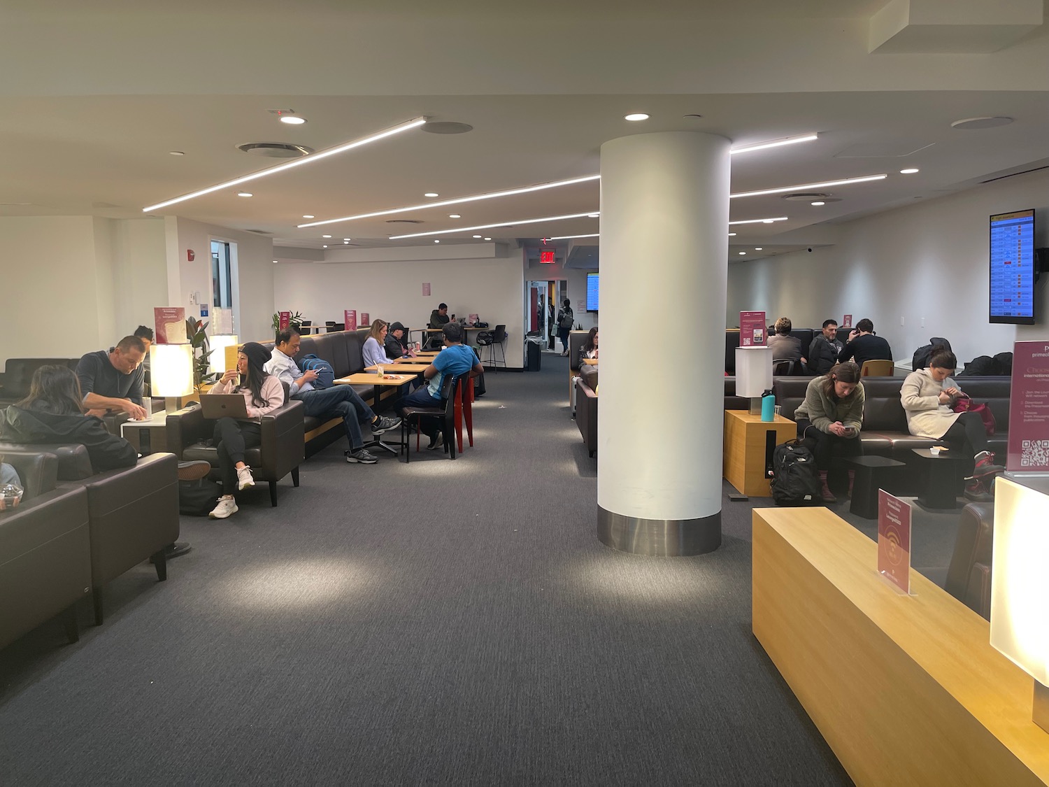 a group of people sitting at tables in a room with a column