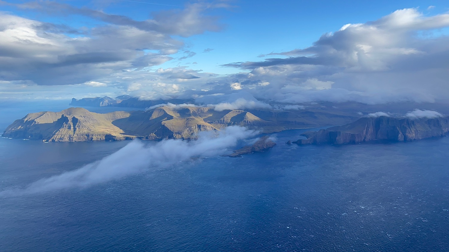 a landscape of a body of water with mountains and clouds